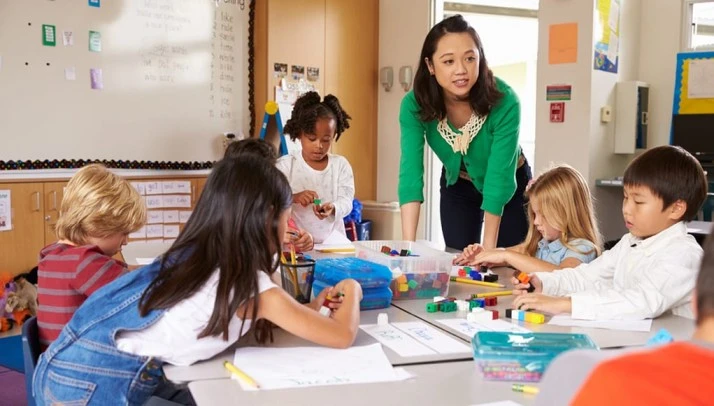 A teacher closely supervises an activity, ensuring a smooth school transition for students.