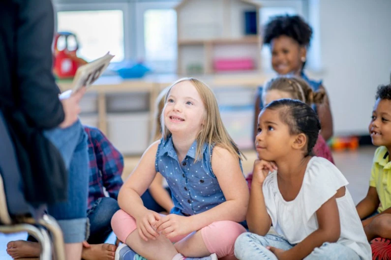 Group of children seated attentively, actively listening during a school transition.