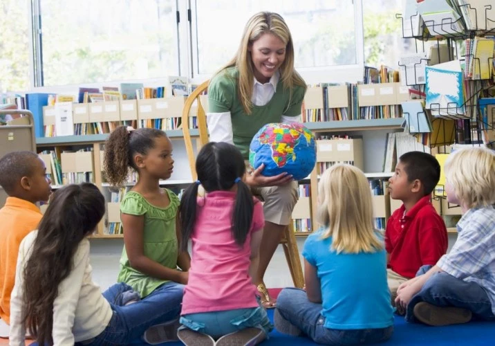 Kids sitting in a circle around a teacher, participating in a social skills activity