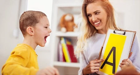 A therapist working closely with a child during a speech therapy session