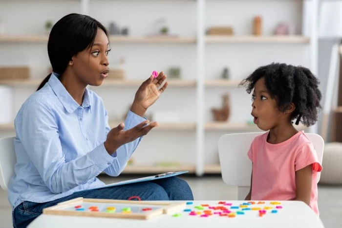 A language therapist working closely with a child during a language therapy session